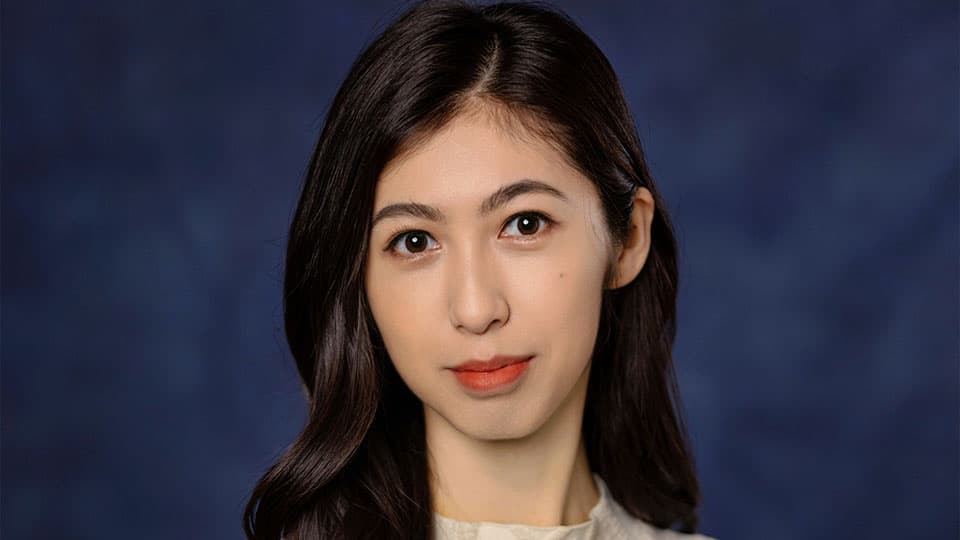 A headshot of Sixian Liu. She is smiling and standing against a blue background.
